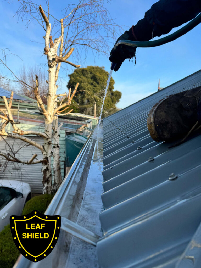 Leafshield gutter cleaner flushing the gutter with a hose